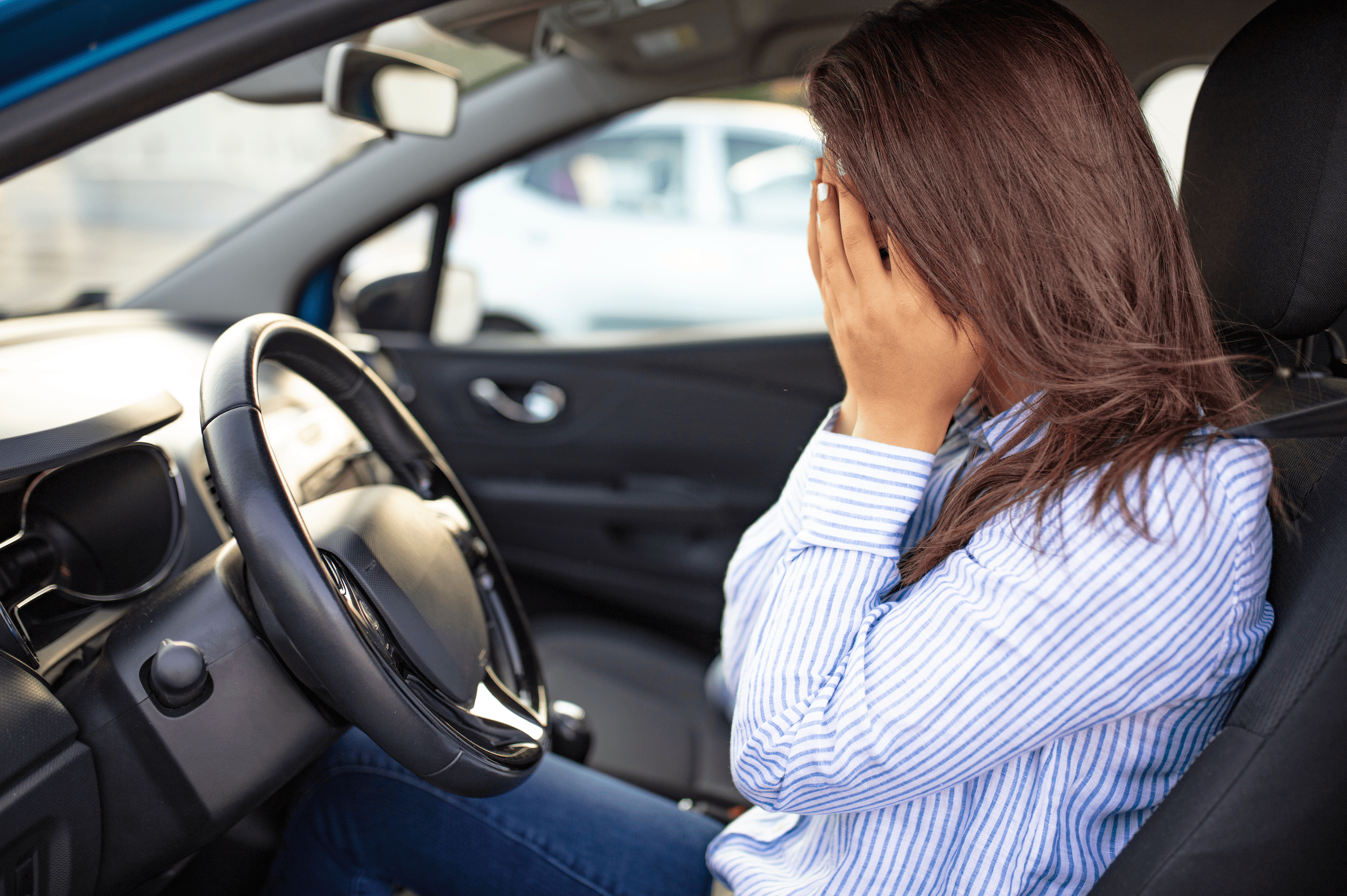Femme dans une voiture se prenant la tête dans les mains par peur