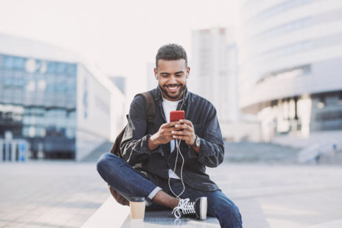 Jeune homme souriant qui regarde son téléphone